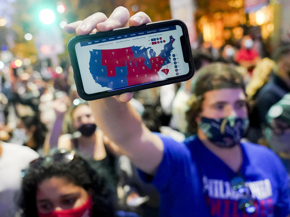 A Joe Biden supporter holds up a phone displaying the Electoral College map in Philadelphia on Nov. 7.