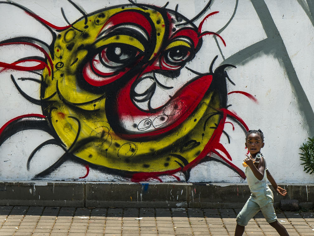 A child walks past a COVID-19 graffiti in Soweto's Orlando West township near Johannesburg, South Africa, on Thursday. Africa has surpassed 2 million confirmed coronavirus cases as the continent's top public health official warns that 