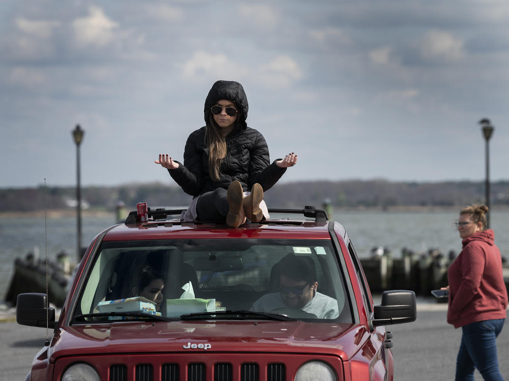 A member of Jesus' Church prays on top of a car during a Sunday church service held at Great Marsh Park in Cambridge, Maryland, on March 22, 2020.