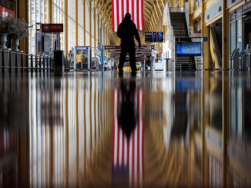 An airport employee walks through Reagan National Airport in Arlington, Va., earlier this year. On Thursday, the Centers for Disease Control and Prevention warned that Americans should refrain from traveling for the upcoming holiday.