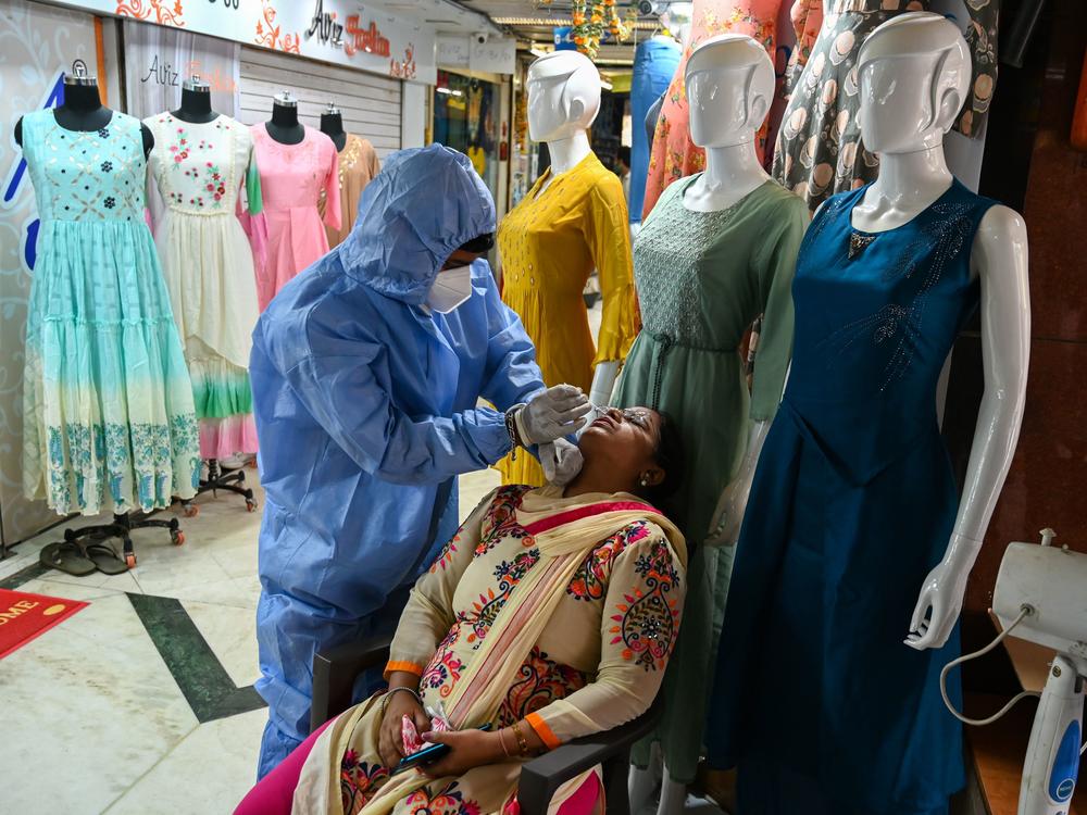 A health worker wearing protective gear collects a swab sample from a woman during a medical screening for the Covid-19 coronavirus at a garment wholesale market in Mumbai, India, on Friday.