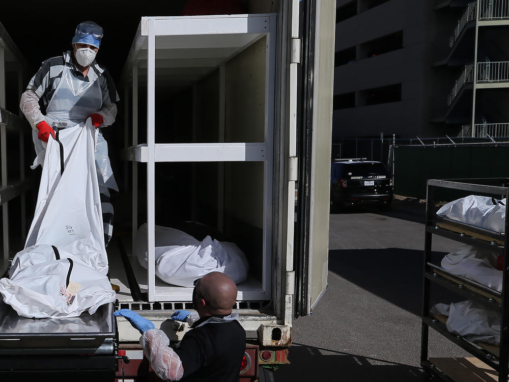 A low-level inmate from El Paso County detention facility works loading bodies wrapped in plastic into a refrigerated temporary morgue trailer in a parking lot of the El Paso County Medical Examiner's office on Tuesday.