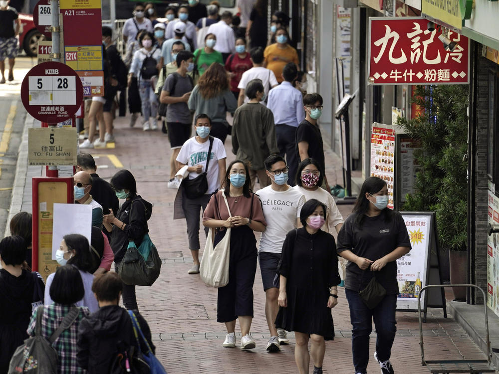 In this Oct. 9, 2020, photo, people walk down a street in Hong Kong. Singapore and Hong Kong have postponed a planned air travel bubble meant to boost tourism amid a spike in coronavirus infections in Hong Kong.