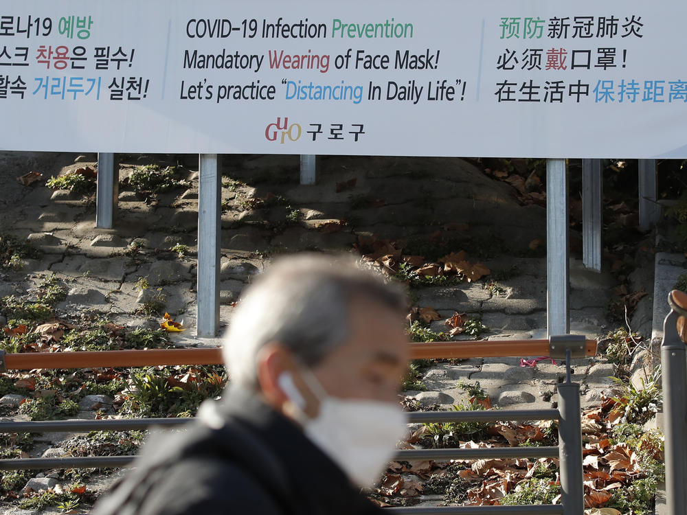 A man wearing a face mask walks past a banner showing precautions against the coronavirus in Seoul on Monday.