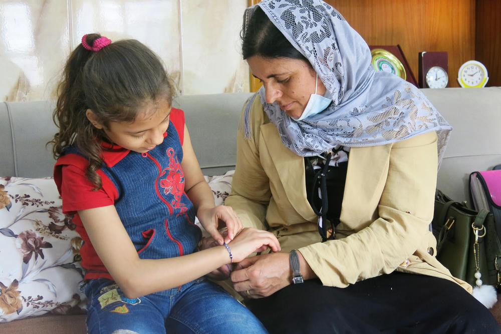 Kamo Zandinan sits in a Mosul orphanage with the 10-year-old she believes is her daughter Sonya, admiring the blue bead bracelet Zandinan has given her. Zandinan is waiting for the results of a DNA test to determine whether the girl, who has been raised by an Arab family, is hers.