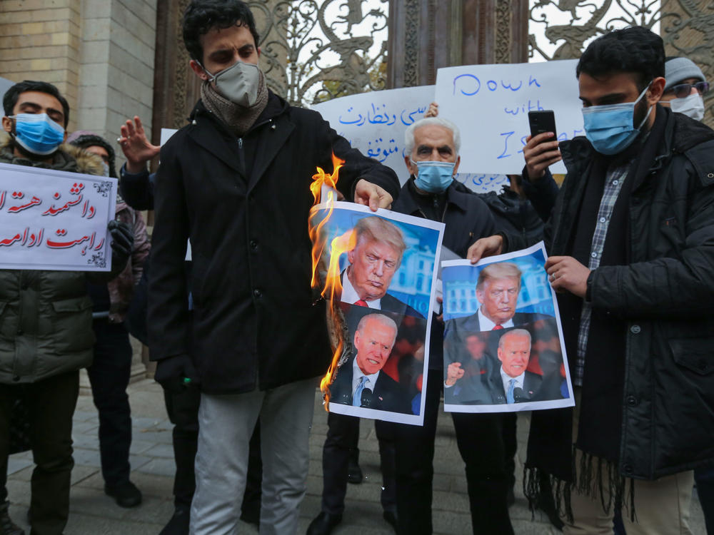 Iranian protesters burn images of President Trump and President-elect Joe Biden during a rally Saturday in  Tehran. Iranian leaders have blamed Israel and its close ally, the U.S., for the assassination of a top Iranian nuclear scientist.