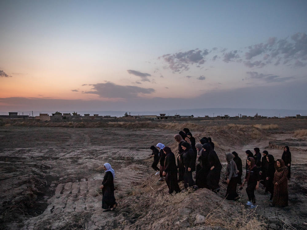 Survivors of the ISIS genocide of Yazidis walk to mass graves near the village of Kocho, northern Iraq, in August 2019, on the fifth anniversary of the massacre that killed most of the men and older boys in the village.