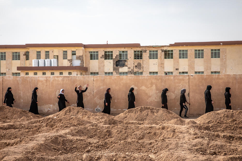 A procession of survivors makes its way to mass graves near the village of Kocho containing the bodies of their loved ones, on the fifth anniversary of the start of the ISIS genocide against Yazidis. ISIS rounded up everyone in the village at gunpoint in the school past the wall, shooting men and older boys and taking women and children captive.