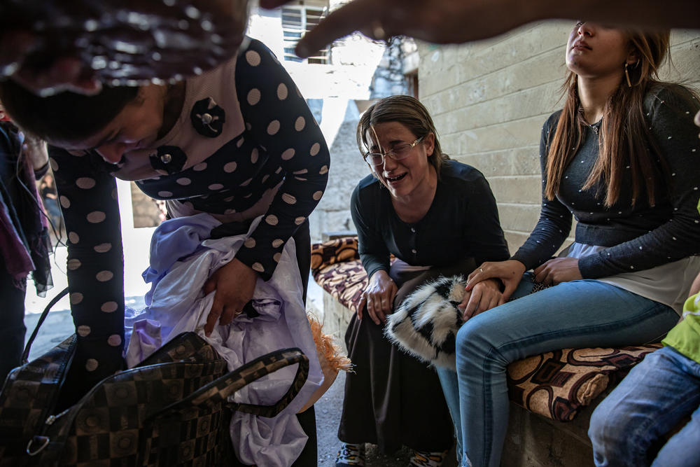 Khairya Murad (right), the sister of Nobel Peace laureate Nadia Murad, and other women from Kocho are overcome with emotion at the Yazidi temple in Lalish. They have brought clothing to be blessed and sprinkled with sacred spring water as part of the burial rites for their family members once the remains are exhumed from mass graves and identified through DNA tests.