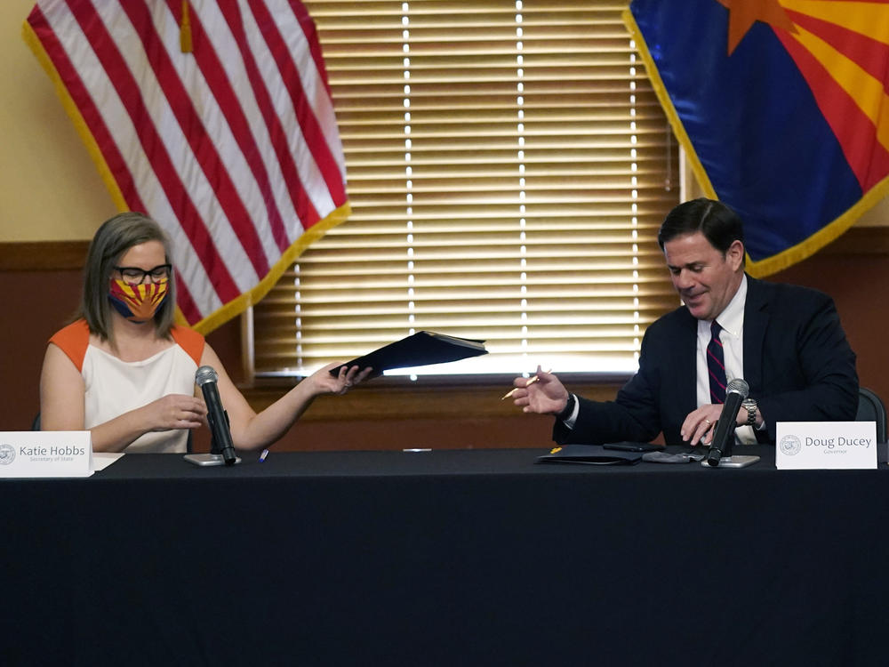 Arizona Secretary of State Katie Hobbs and Gov. Doug Ducey exchange election documents as they certify election results Monday at the Arizona Capitol in Phoenix.