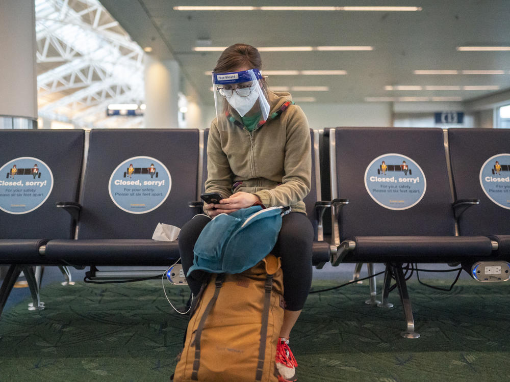 A traveler waits for a flight at Portland International Airport in Oregon last week. Public health experts say it's important that people who traveled or gathered with others are especially careful over the next two weeks.