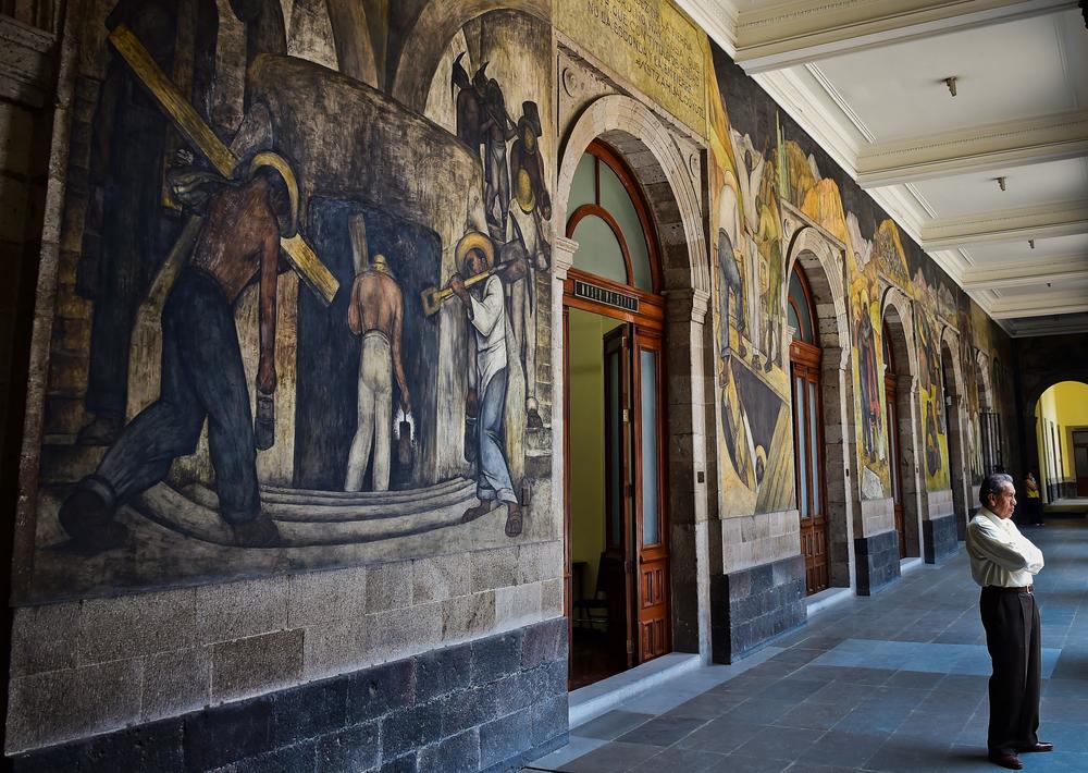 A man stands next to murals by Diego Rivera in the Education Secretariat in Mexico City in April 2017.