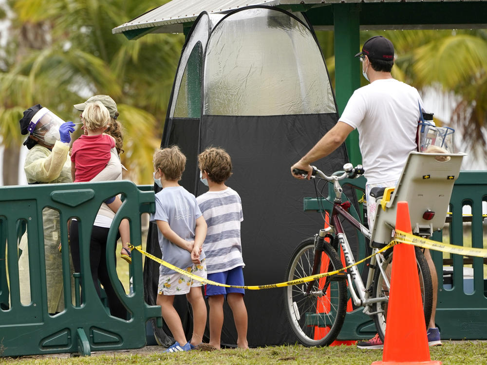 A health care worker (left) administers a coronavirus test at a mobile walk-up testing site at Crandon Park in Miami last month.