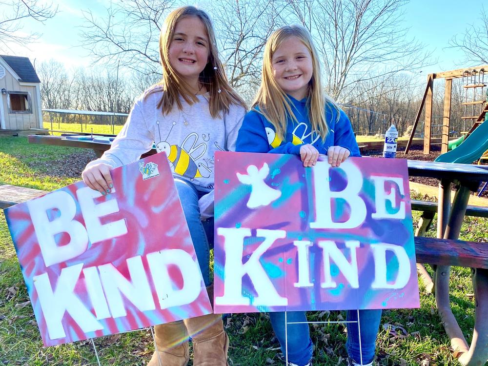 On a November afternoon sisters Raegan and Rylyn Richins sit at their picnic table in their backyard in a Kentucky county holding signs they just painted.