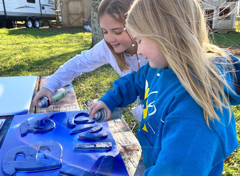 Sisters, Raegan and Rylyn Richins look closely at one of their newly painted 