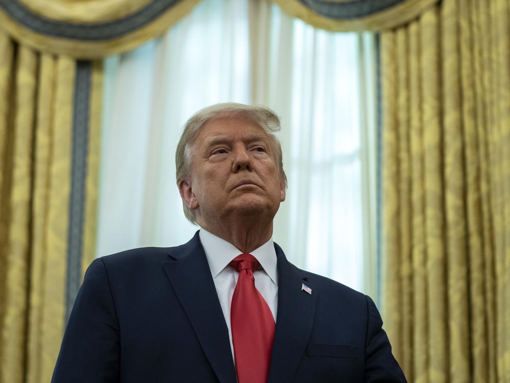 President Trump listens during a ceremony Thursday to present the Presidential Medal of Freedom to former college football coach Lou Holtz in the Oval Office.