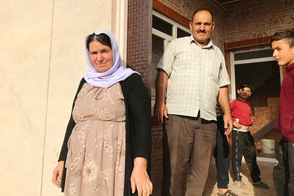 Nofa Khudeda (left) and her husband Ali Edo with neighborhood children just minutes after the couple arrived home in their village of Tel Qasab after six years in a camp for displaced Yazidis.