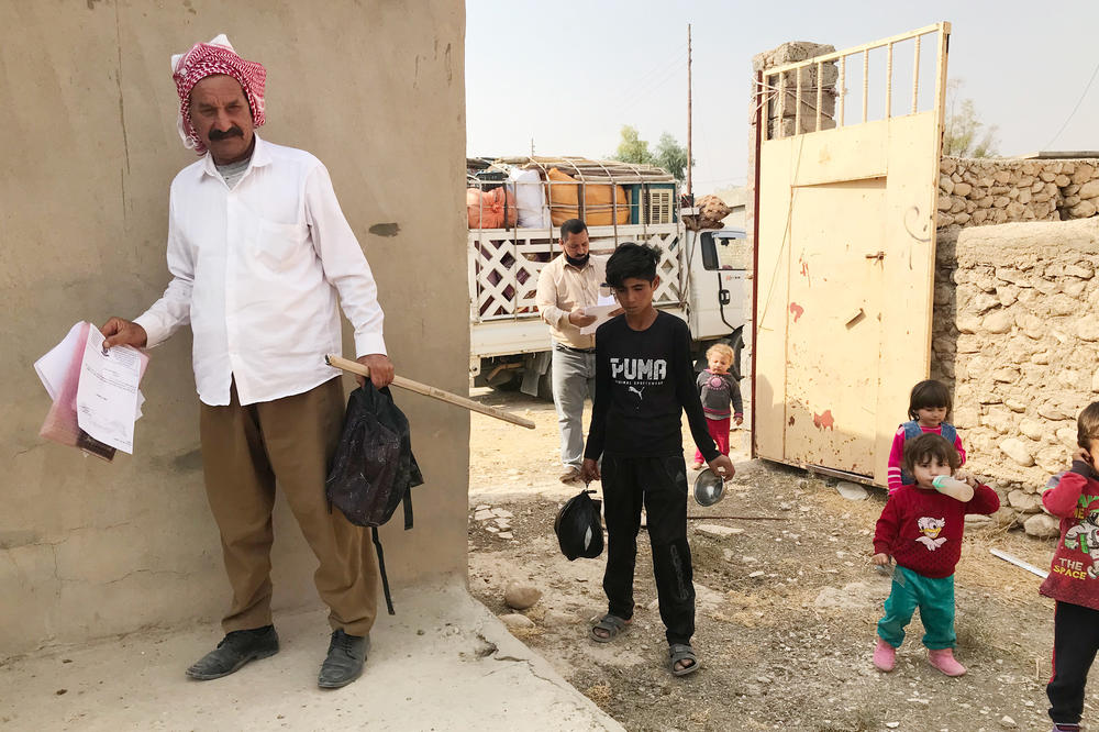 Hassan Murad returns to his damaged home in the village of Wardiya, in Sinjar province, with his wife and five young children. He holds the official documents he needed to return. A teenager from the village helps carry things in.