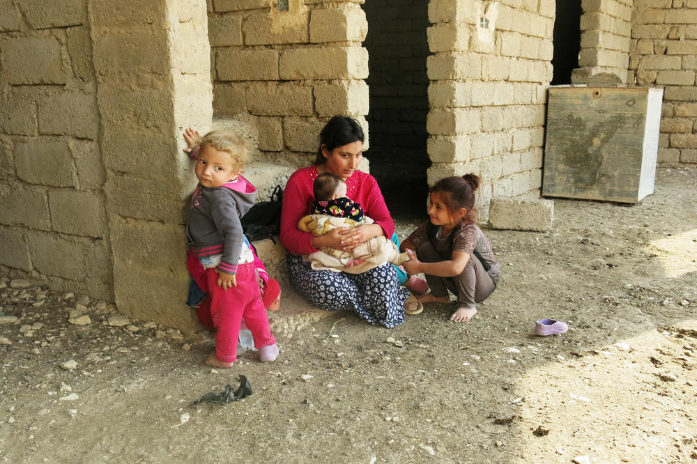 Wadha Ammo holds her youngest of five children while a girl from the village admires the baby. Ammo married her husband, Hassan Murad, while living in a displacement camp and this is the first time she has seen their new home.