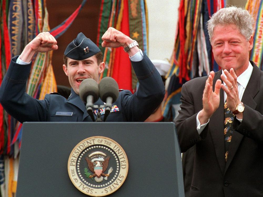 President Bill Clinton applauds Air Force pilot Scott O'Grady, who was shot down in Bosnia and survived six days in the woods, in 1995. Now a Trump supporter and tapped for a top Pentagon job, O'Grady has been endorsing baseless conspiracy theories related to the election.
