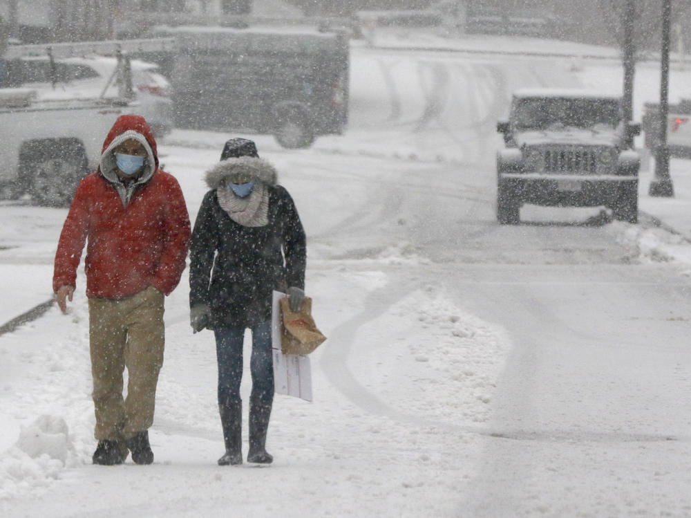 A couple walks through heavy snow on Saturday in downtown Marlborough, Mass. The northeastern United States is seeing the first big snowstorm of the season.