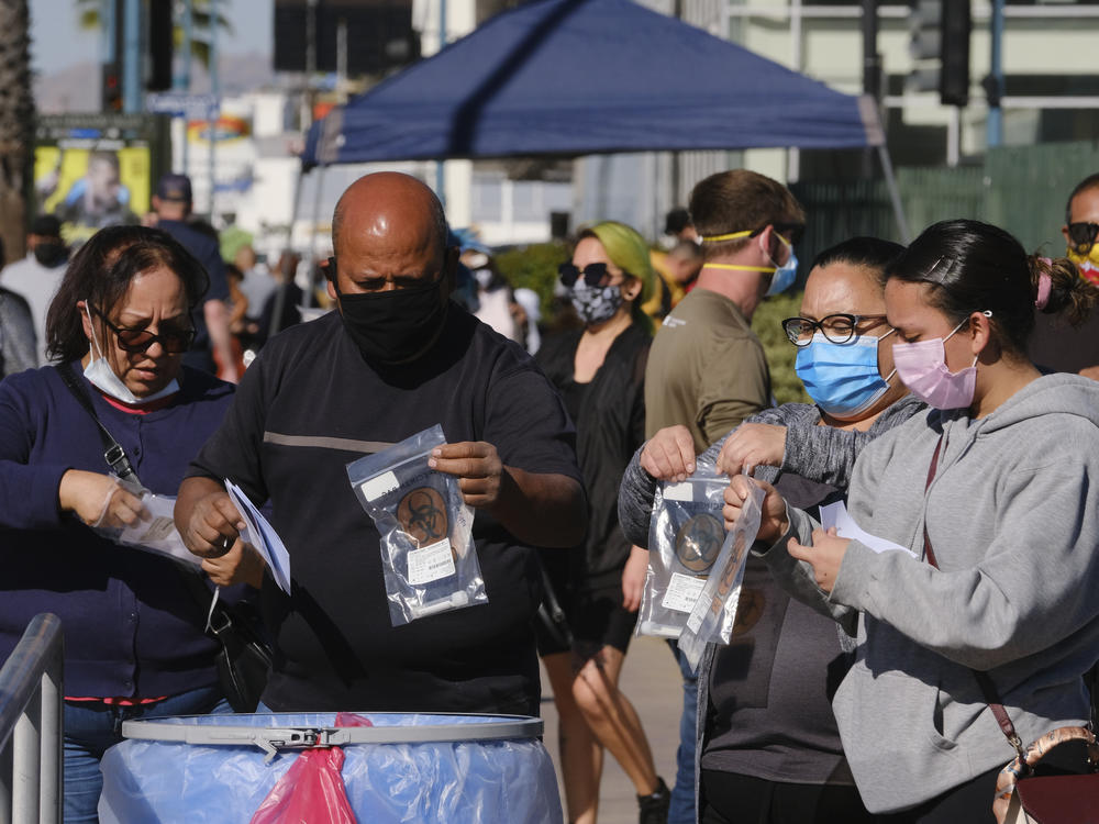 People drop their test kits into a receptacle at a coronavirus testing site in the North Hollywood section of Los Angeles on Saturday. With COVID-19 cases surging at a record pace in California, Gov. Gavin Newsom has warned that the state's hospitals could soon be overwhelmed.