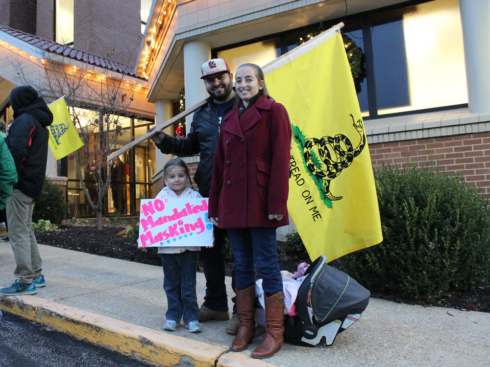 Outside City Hall on the evening of a vote on a proposed mask order in Washington, Mo., residents Ali and Duncan Whittington protest against the order, along with their 4-year-old daughter. 