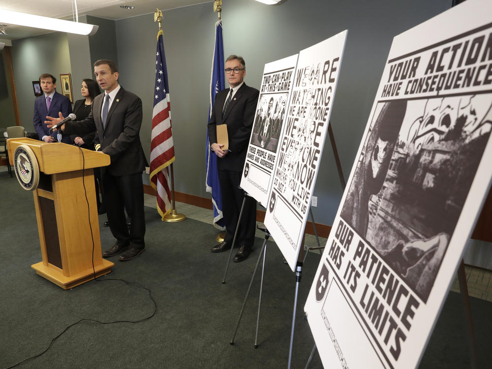 Raymond Duda, FBI Special Agent in Charge in Seattle, speaks in February about charges against a group of alleged members of the neo-Nazi group Atomwaffen Division for cyber-stalking and mailing threatening communications, including the posters at right, in a campaign against journalists in several cities.