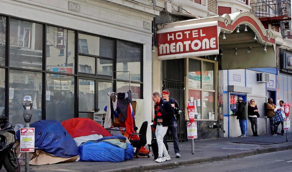 Pedestrians walk to the edge of the sidewalk to avoid stepping on people in tents and sleeping bags in the Tenderloin area of San Francisco on April 13. Due to the coronavirus pandemic. California Gov. Gavin Newsom launched 