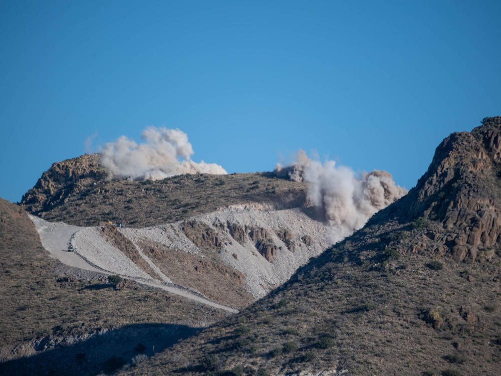 Dynamite raises clouds of dust above Guadalupe Canyon, near the New Mexico-Arizona border. The Diamond A Ranch, which is located next to the construction site, has sued the government, claiming the blasting has sent 