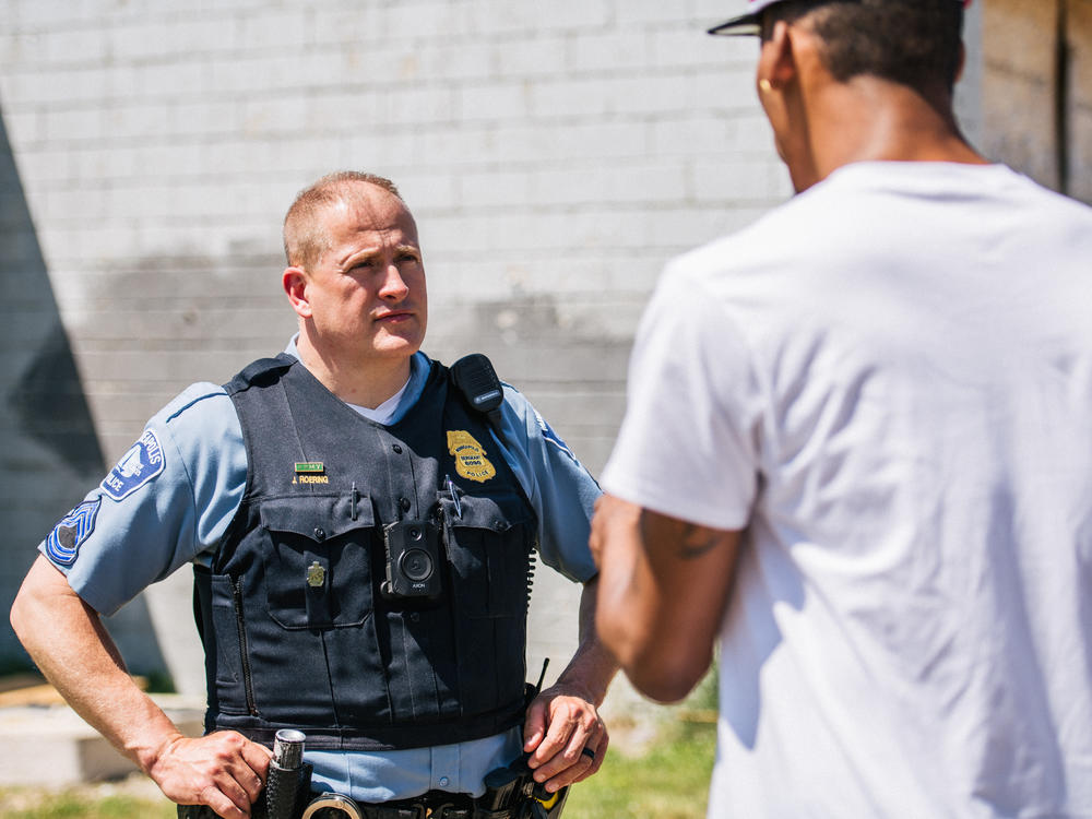 A man speaks with a Minneapolis Police officer at a crime scene on June 16. The Minneapolis City Council voted Thursday to shift $8 million in police funding to other services.