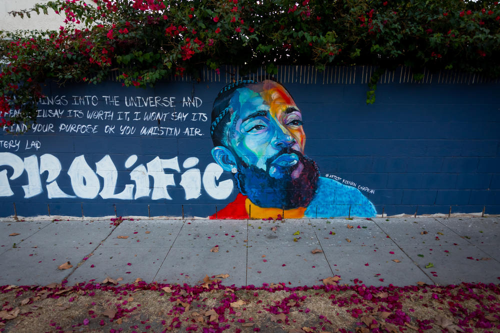 A mural of Nipsey Hussle is ringed by flowers on Brynhurst Ave. in Crenshaw Dec. 5, 2020. In the wake of Nipsey Hussle's March 2019 death, many murals of the beloved Los Angeles musician were painted in the Hyde Park neighborhood near his Marathon clothing store. The store and a large Nipsey mural in its alleyway is now fenced off but other nearby murals continue to draw local and visiting fans.