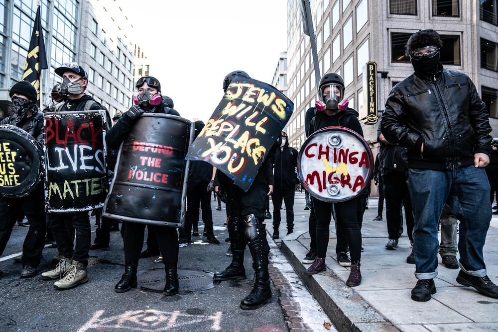 Counterprotesters form a line behind a police line while chanting, 