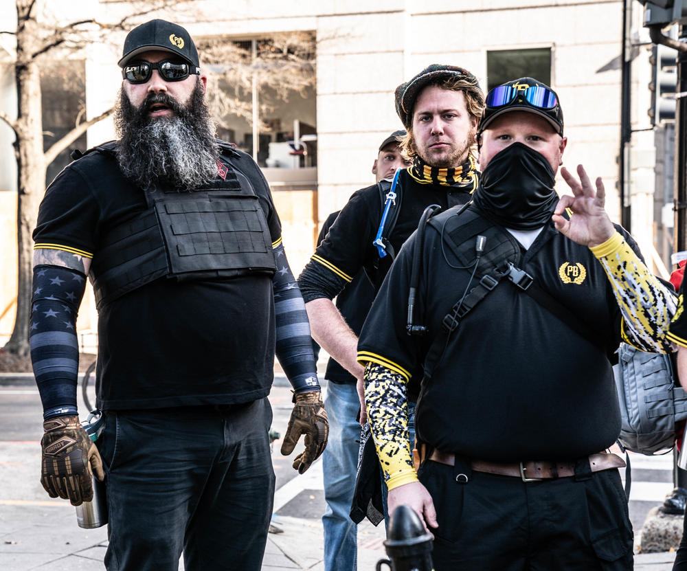 A member of the Proud Boys makes a white power hand gesture.