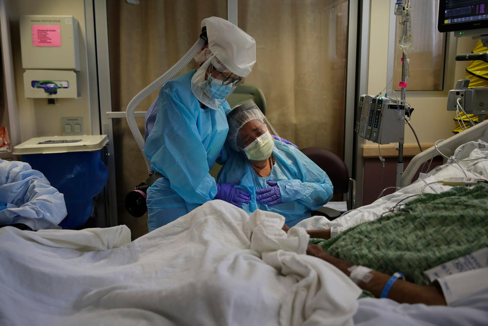 Nurse Michele Younkin (left) comforts Romelia Navarro as she sits at the bedside of her dying husband, Antonio Navarro, in St. Jude Medical Center's COVID-19 unit in Fullerton, Calif., in July. Antonio Navarro was Younkin's first COVID-19 patient to pass on her watch.
