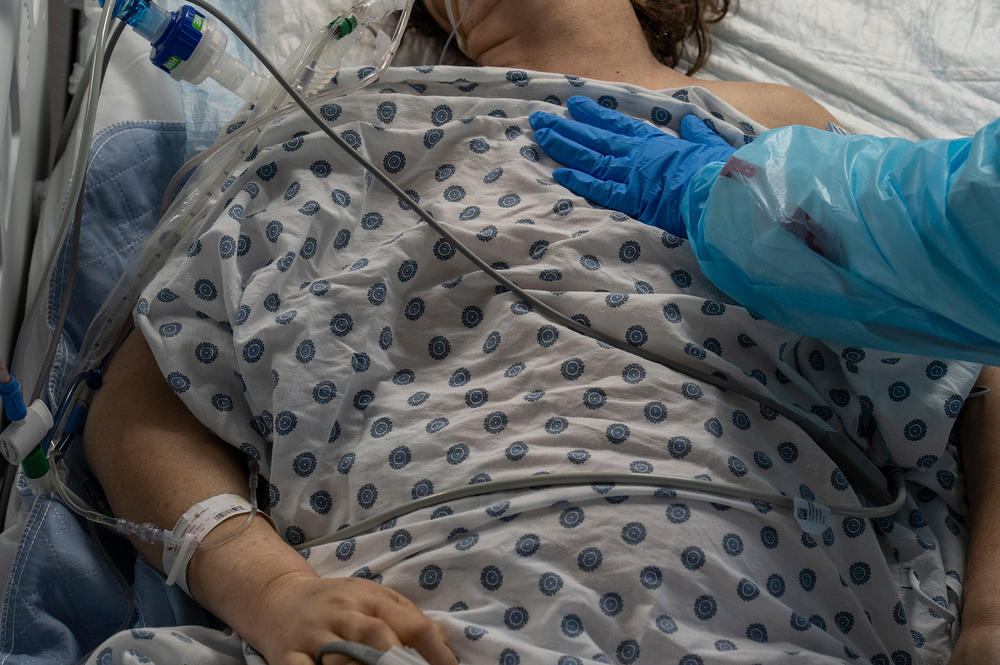 Medical staff member Susan Paradela places her hand on a patient last week in the COVID-19 intensive care unit at United Memorial Medical Center in Houston.