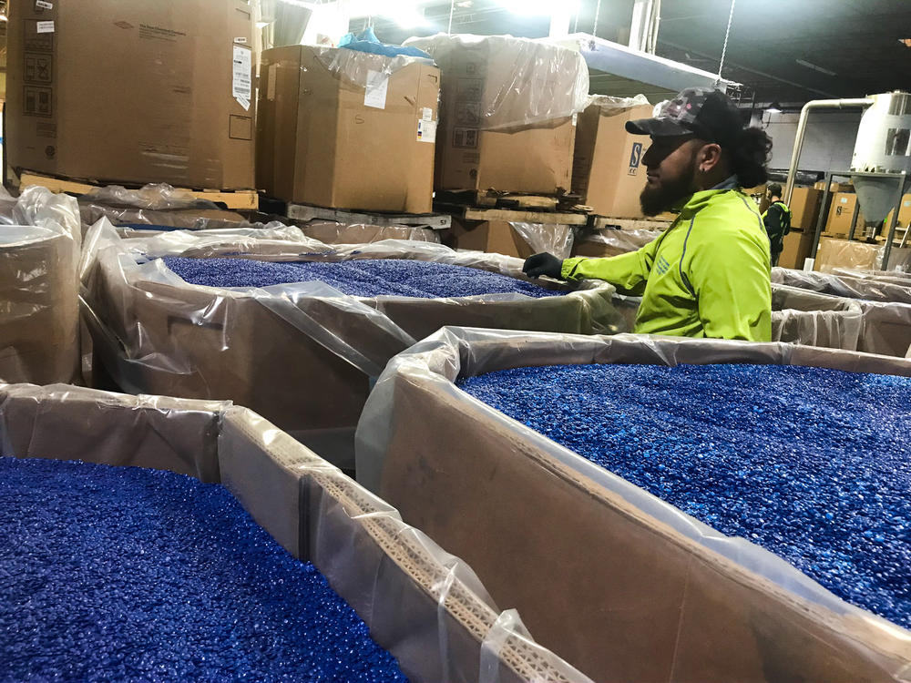 A worker at a plant in New Jersey inspects the quality of pellets. Melt 350 of them, and you get a yogurt cup. Melt 1,000, and you get a water bottle.