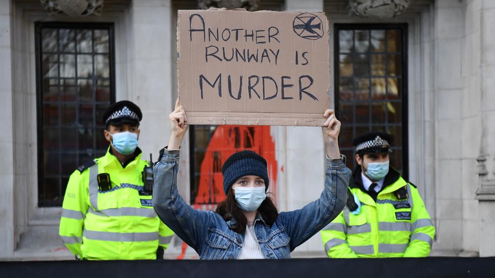 A demonstrator raises a sign protesting plans for a third runway in London, the same day that the British Supreme Court reopened the door to the runway. The runway had previously been blocked on environmental grounds.