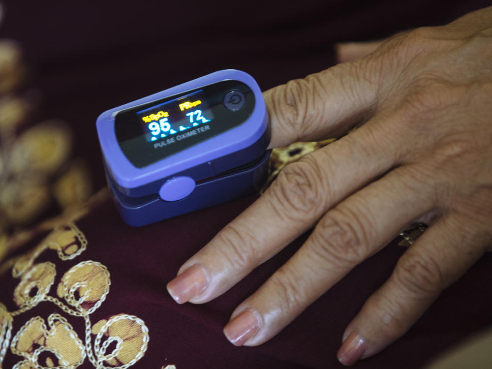 A paramedic uses a pulse oximeter to check a patient's vital signs during an August home visit in the Bronx borough of New York.