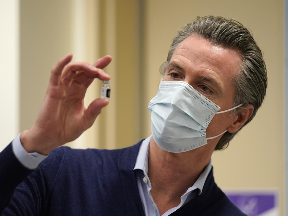 California Gov. Gavin Newsom holds up a vial of the Pfizer-BioNTech COVID-19 vaccine this week at a Los Angeles medical facility. Coronavirus cases continue to soar in the state as hospitals struggle to keep up with the surge.