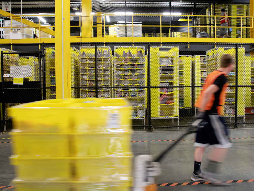 A worker pulls a pallet jack with plastic crates at an Amazon warehouse in Robbinsville, N.J. The company is facing its biggest labor battle yet with a unionization vote expected at a facility in Alabama.