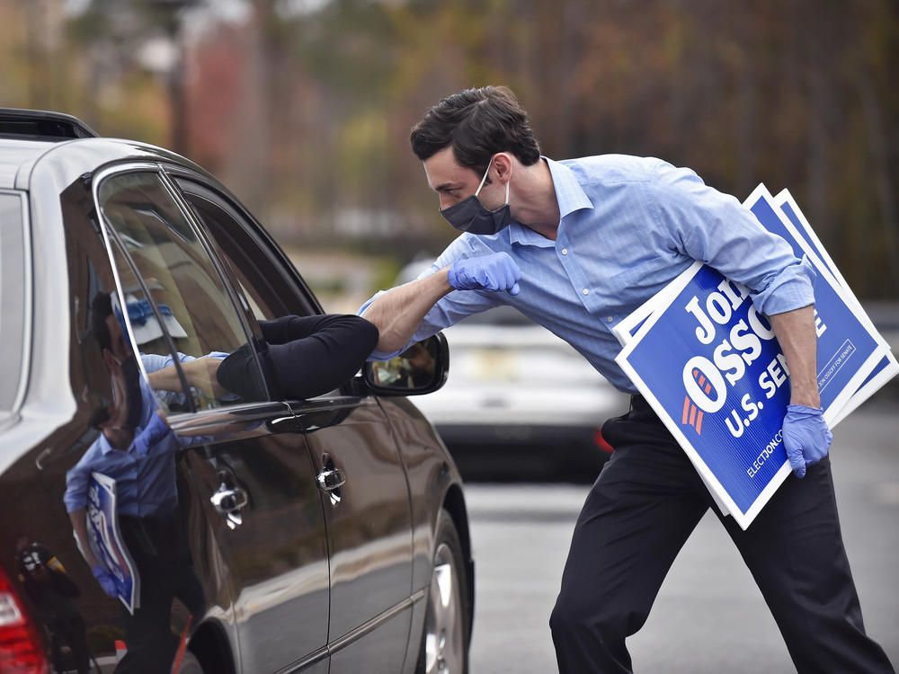Jon Ossoff, a Georgia Democratic candidate for U.S. Senate, greets a supporter with an elbow bump at a drive-through event to pick up yard signs last month in Alpharetta, Ga. Ossoff is in a runoff with Republican David Perdue, the incumbent, for the U.S. Senate.