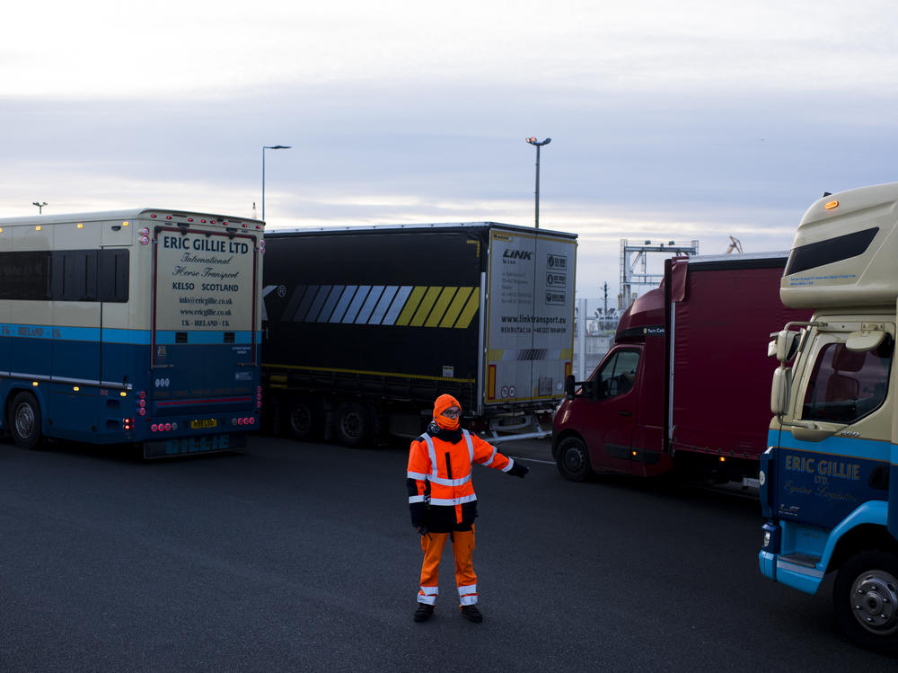 A worker directs trucks where to wait in line in order to board ferries to the United Kingdom in Calais, France. Twenty percent of British imports pass through the port of Calais.