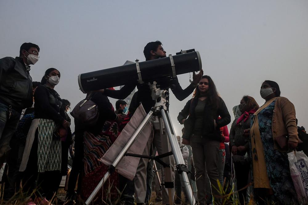 People stand in a queue to see the Great Conjunction at the Maidan area in Kolkata, India.