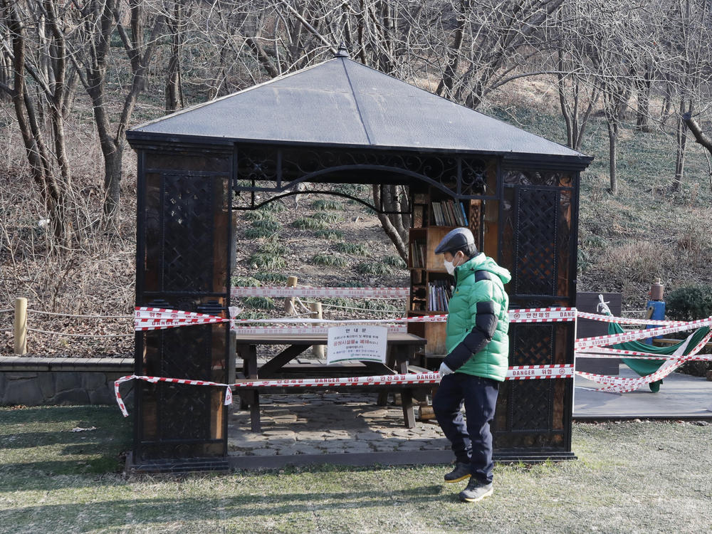 A man wearing a face mask walks past a rest area taped for social distancing as a precaution against the coronavirus in Seoul, South Korea, on Tuesday.