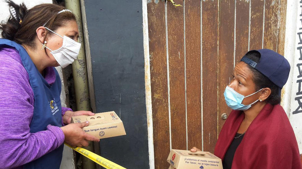 Marta Duque hands out food to a migrant from Venezuela.
