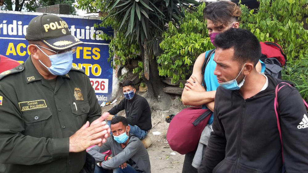 Jose Paéz (right), who migrated from Venezuela, pleads with a Colombian police officer. He was detained with about 50 other people at a roadblock in Pamplona.