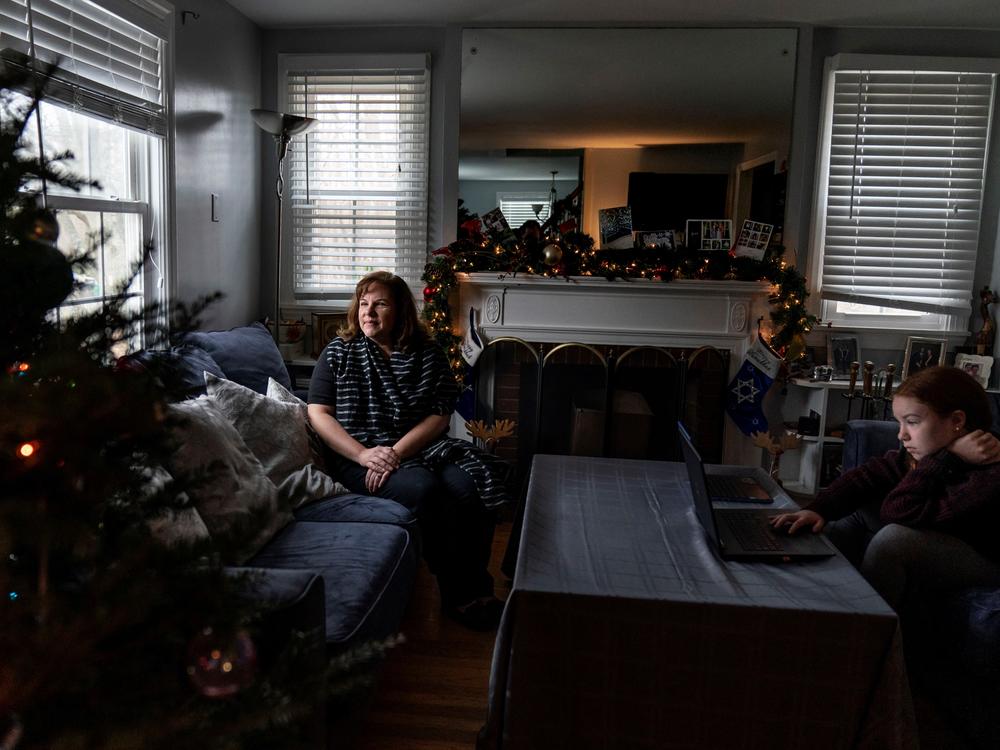 Eileen Carroll, left, sits for a portrait as her daughter, Lily, 11, attends school remotely from their home in Warwick, R.I. on Dec. 16. When Carroll's other daughter tested positive for the coronavirus, state health officials told her to notify anyone her daughter might have been around. Contact tracers, she was told, were simply too overwhelmed to do it.