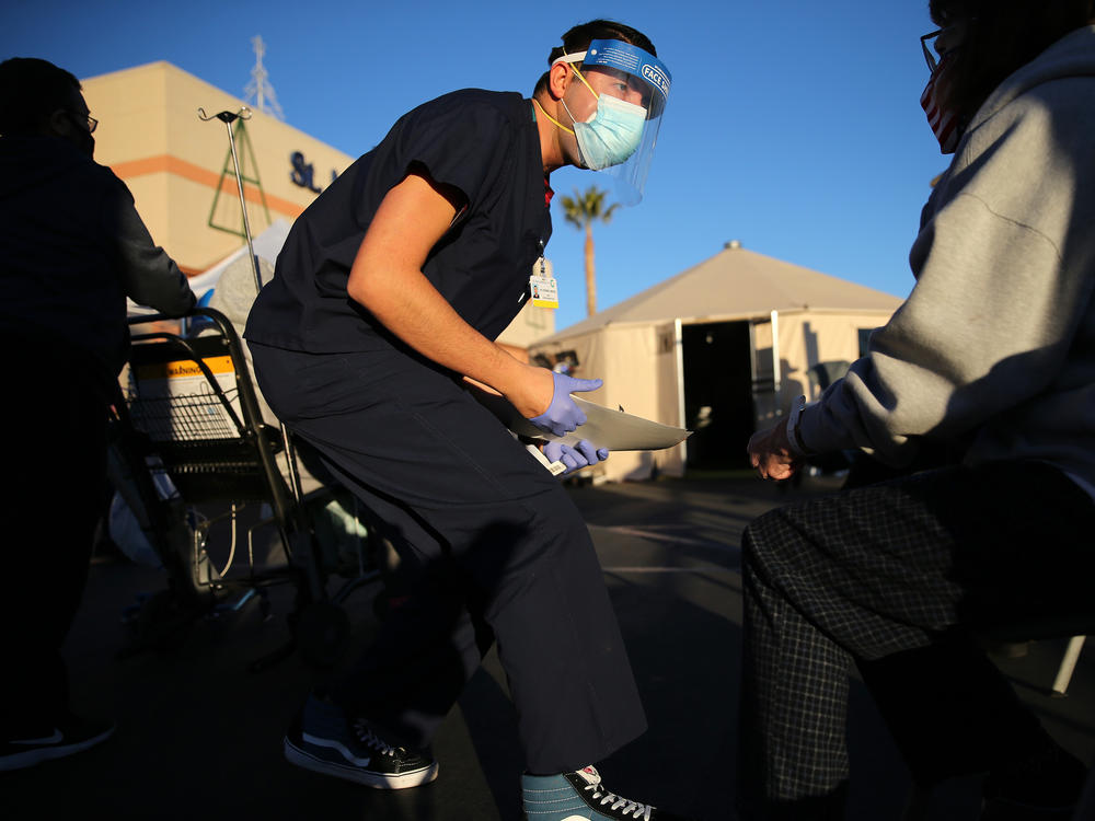 A California National Guard medic prepares to check the vital signs of an incoming patient in front of triage tents outside St. Mary Medical Center last week in Apple Valley amid a surge in COVID-19 patients in Southern California.