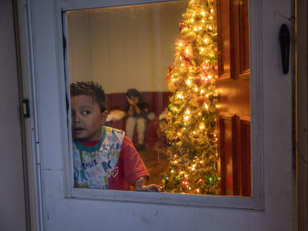 Mario, 7, looks from his family's home in Stamford, Connecticut, on Dec. 24, 2020. The Guatemalan immigrant family, with multiple generations living under the same roof, are recovering from the coronavirus while trying to celebrate Christmas. Eight of 10 family members are COVID-19 positive. Mario, a special needs child, has tested negative for the virus.